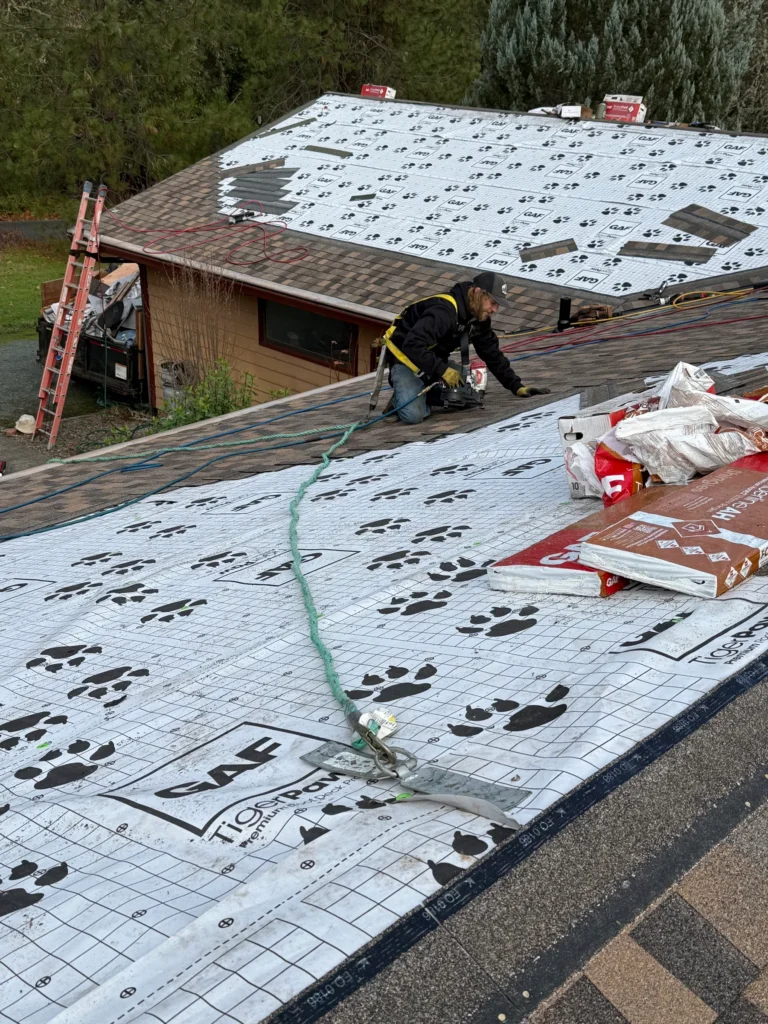 Roofer installing shingles over roof underlayment